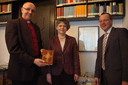 Bischof Hans-Jörg Voigt, Verlegerin Dr. Reinhilde Ruprecht und Geschäftsführender Kirchenrat Michael Schätzel mit einem Exemplar der Taufagende vor der Magdeburger Erklärung zur gegenseitigen Anerkennung der Taufe